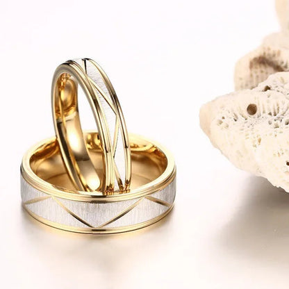 Two gold wedding rings with a geometric pattern on a white background