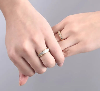 Two hands with gold rings on a gray background