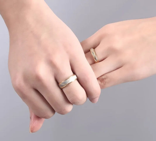 Two hands with gold rings on a gray background