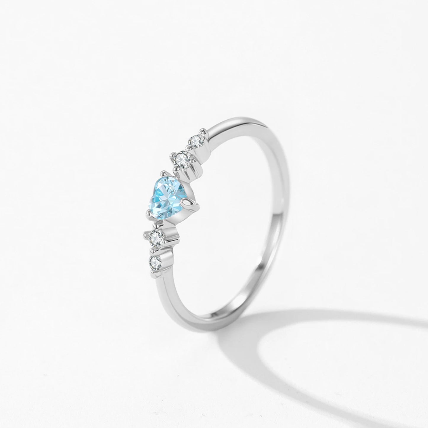 Silver ring with a heart-shaped blue gemstone on a white background