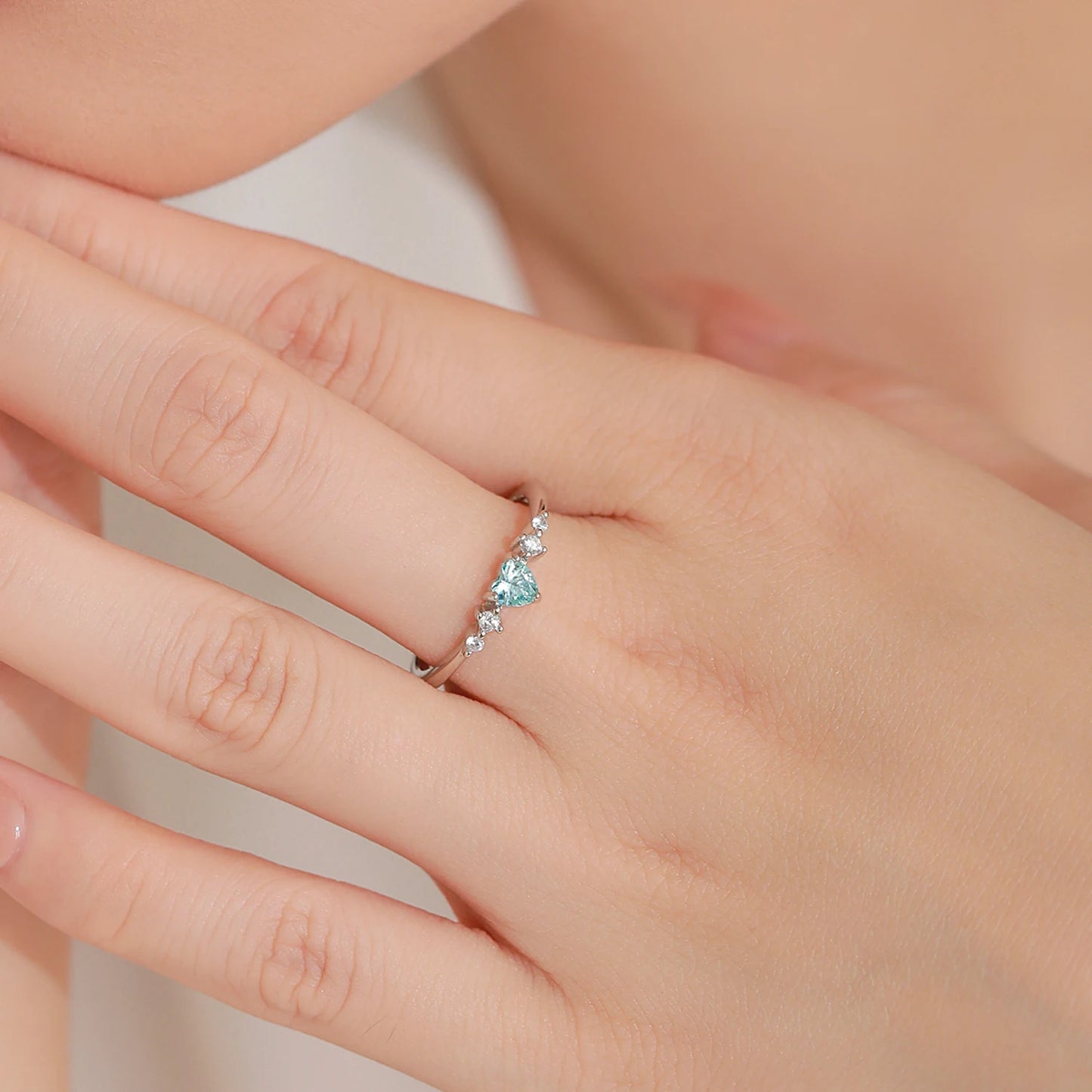 Close-up of a hand wearing a silver ring with a blue heart CZ 