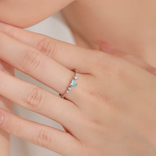 Close-up of a hand wearing a silver ring with a blue heart CZ 